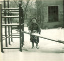Small girl playing with snow on a slide, The University of Iowa, January 1938