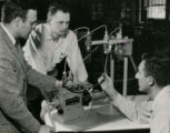Three men work with scientific apparatus in the Farm Machinery Lab, 1957